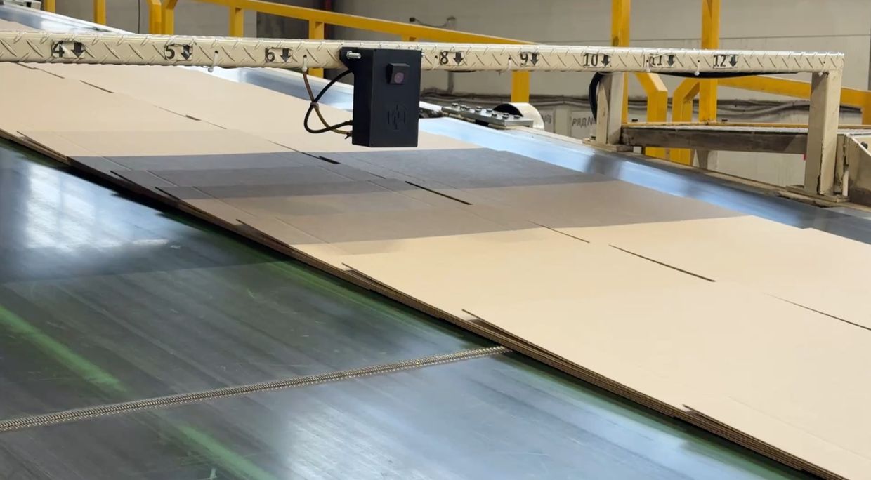 Крупный план датчика контроля коробления картона на производственной линии